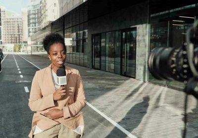 African news reporter with microphone live broadcasting on street